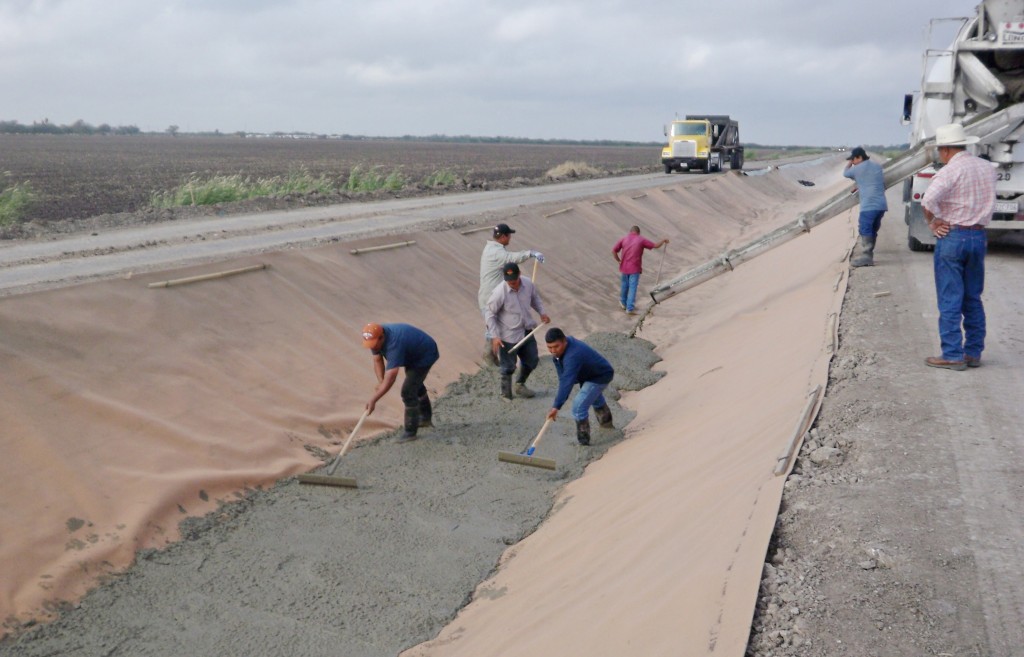 Workers in Hidalgo County spread concrete over a synthetic canal liner made of polyester. Historically, irrigation canals were basically just earthen ditches, according to Dr. Guy Fipps, Texas A&M AgriLife Extension Service irrigation engineer, College Station. But due to the burgeoning water shortages over the past two decades, there has been an increase in the awareness of the need to reduce water loss from canals through seepage. (Texas A&M AgriLife Extension Service photo by Askar Karimov) 