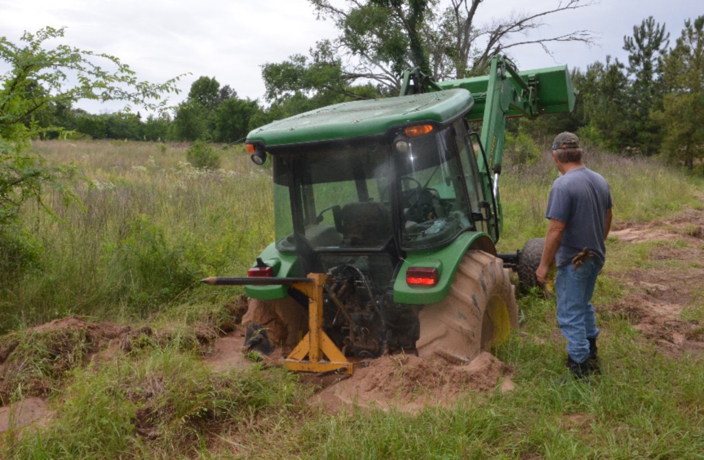 On May 12, Ken Holland, East Texas farm hand, surveys a tractor he and his boss, Malcom Williams, have been trying to get unstuck for weeks. A week ago, Williams said he had two other tractors stuck trying to pull this one out. (Texas A&M AgriLife Extension Service photo by Robert Burns)
